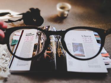 Image of newspaper with someone holding glasses