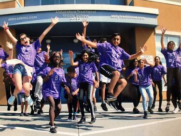 Students jumping with excitement in front of school