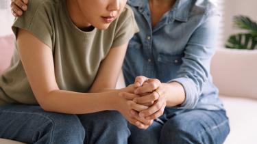 iStock - Parent Consoling Teen Mother holding hands with daughter, consoling the teen