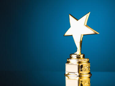 A gold trophy with a star topper on a blue background