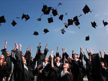 Group of students in graduation attire throwing caps into the air