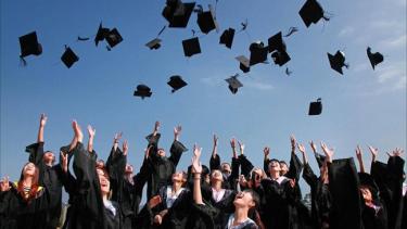 Convocation Group of students in graduation attire throwing caps into the air