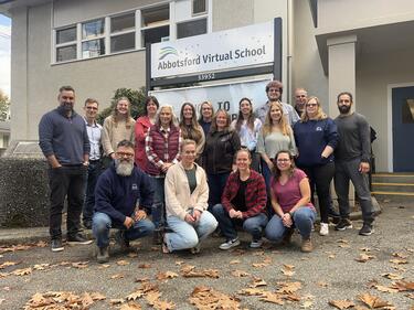 Group staff photo in front of school and their sign