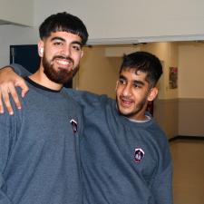 Two students smiling with arm around shoulders