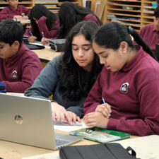 Secondary student assisting middle year student with school work