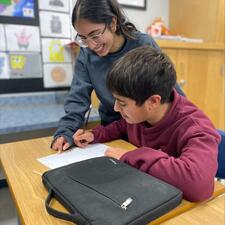 Secondary student assisting middle year student with school work